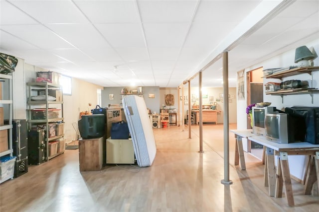 basement with a paneled ceiling and light wood finished floors