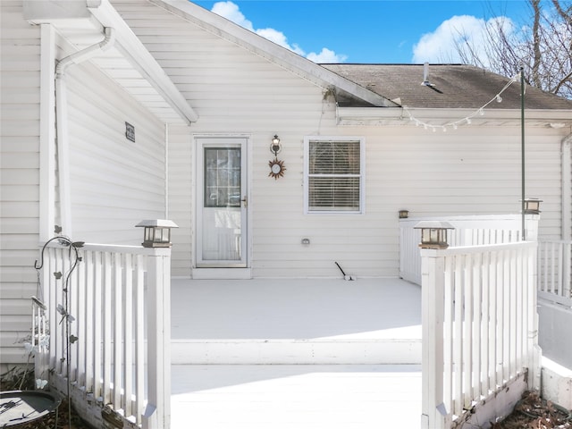 property entrance with a shingled roof and a deck