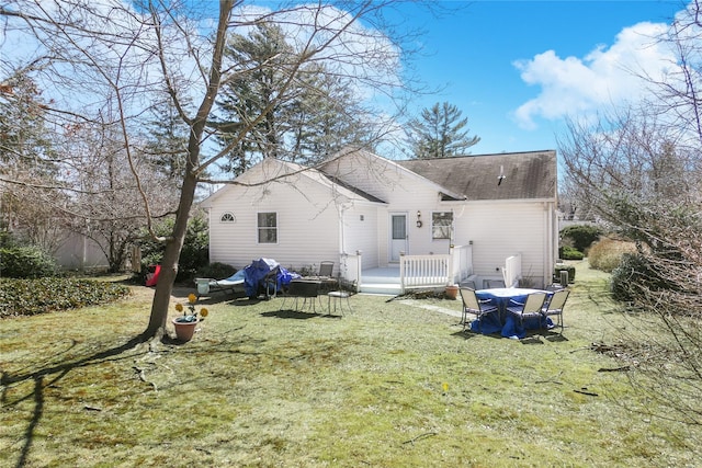 back of property with a wooden deck, a yard, and a shingled roof