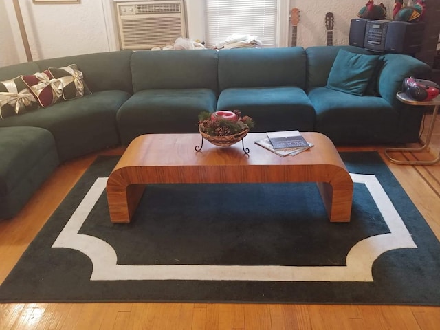 living room with a wall mounted AC, a textured wall, and wood finished floors