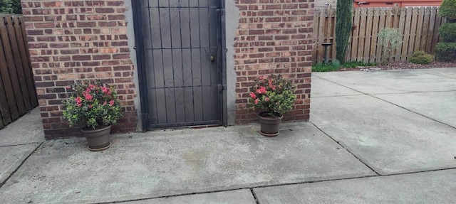 doorway to property featuring a patio, fence, and brick siding