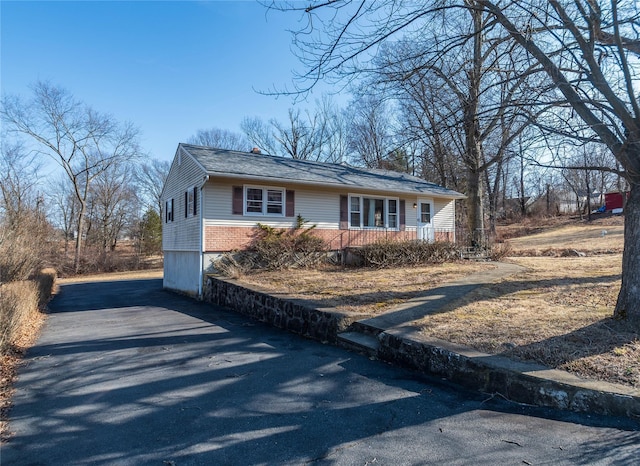 view of front of home with aphalt driveway, brick siding, and a chimney