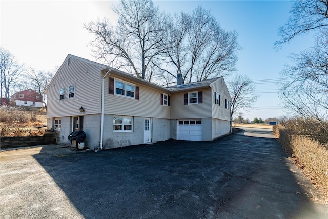 exterior space featuring an attached garage, a chimney, and driveway