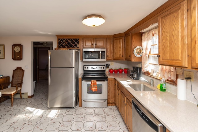 kitchen featuring a sink, light countertops, appliances with stainless steel finishes, brown cabinets, and baseboard heating