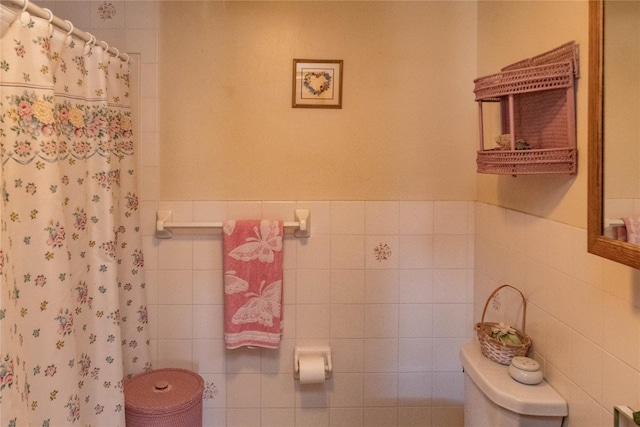 full bath with a shower with shower curtain, toilet, tile walls, and a wainscoted wall