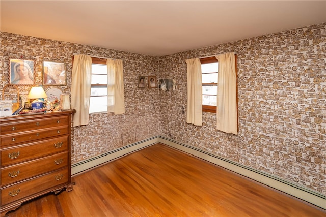 spare room with a baseboard radiator and wood finished floors