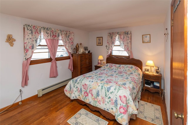 bedroom with a baseboard radiator, baseboards, and wood finished floors