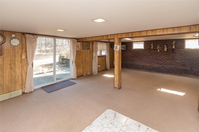 basement with light colored carpet, a healthy amount of sunlight, brick wall, and wooden walls