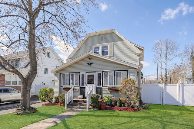 view of front of home with a sunroom, fence, a front lawn, and a gate