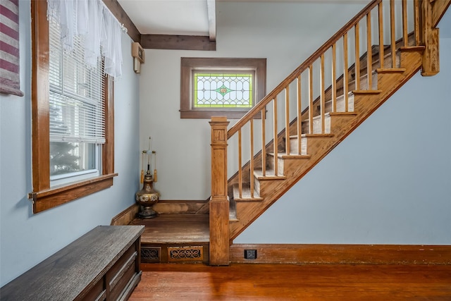 stairway featuring beamed ceiling and wood finished floors