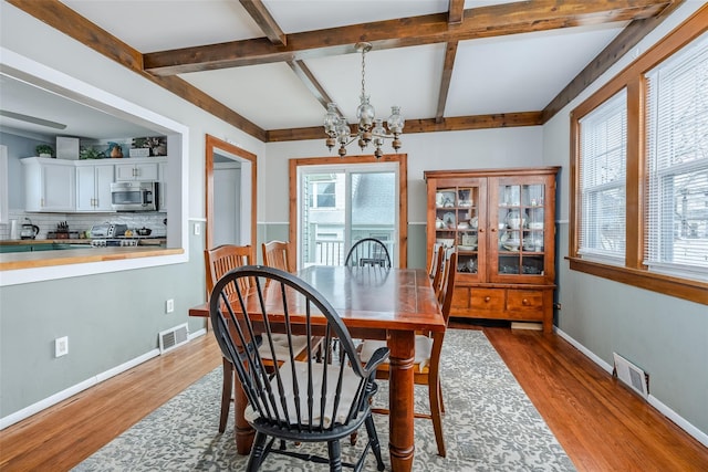 dining space with a chandelier, visible vents, baseboards, and wood finished floors