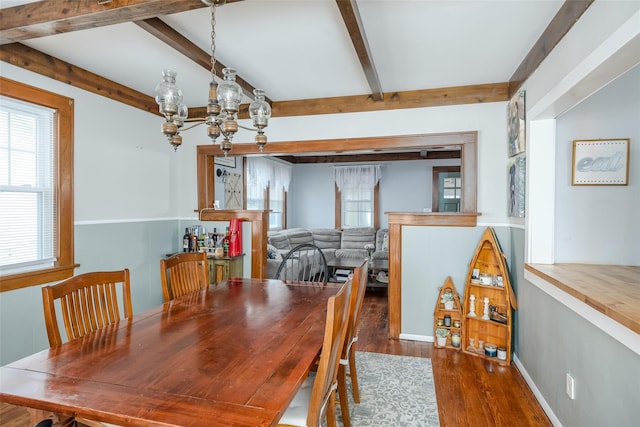 dining area with an inviting chandelier, beam ceiling, wood finished floors, and baseboards