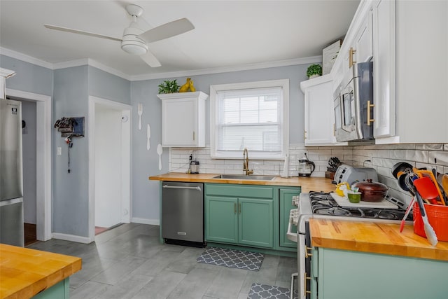 kitchen with wooden counters, green cabinets, ceiling fan, stainless steel appliances, and a sink