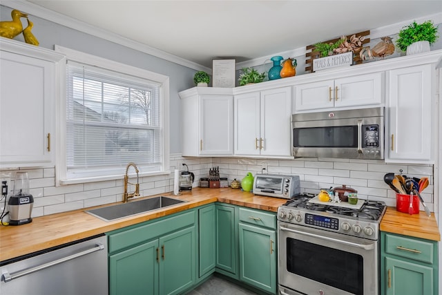 kitchen with a sink, stainless steel appliances, white cabinets, and butcher block counters