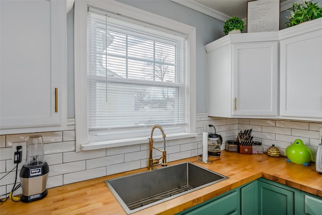 kitchen with a sink, wooden counters, tasteful backsplash, and white cabinets