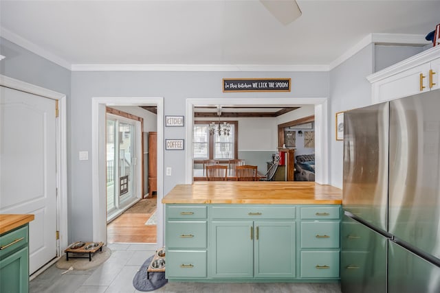 kitchen with light tile patterned floors, wooden counters, freestanding refrigerator, green cabinets, and crown molding