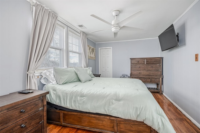 bedroom featuring visible vents, crown molding, ceiling fan, dark wood finished floors, and a closet