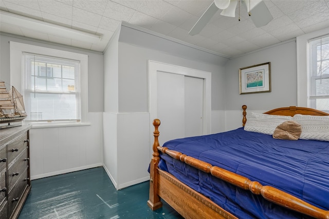 bedroom with a ceiling fan and wainscoting