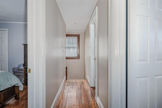 hallway with hardwood / wood-style floors, an upstairs landing, baseboards, and ornamental molding