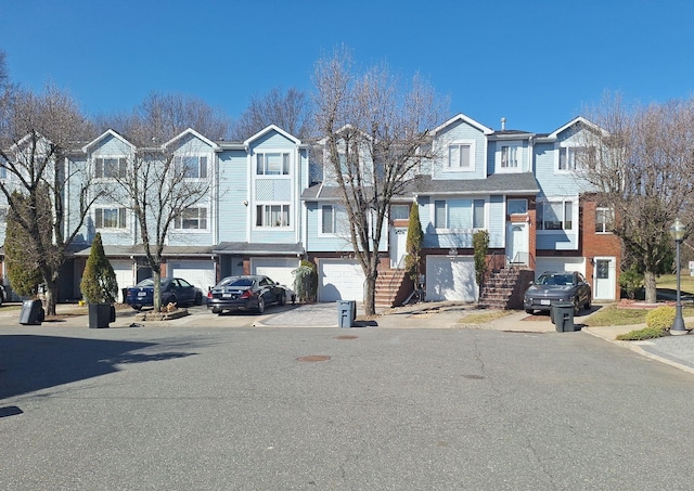 townhome / multi-family property featuring a residential view, driveway, stairway, and a garage