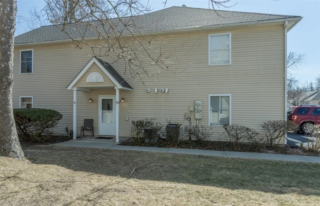 view of front of house with cooling unit, a front lawn, and a shingled roof