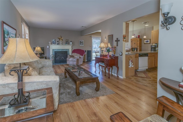 living room with visible vents, a fireplace, light wood-type flooring, and baseboards