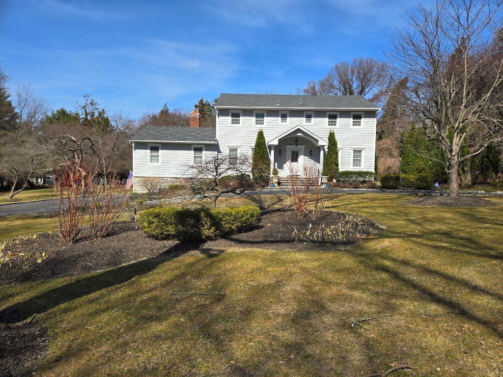 view of front facade with a chimney and a front lawn