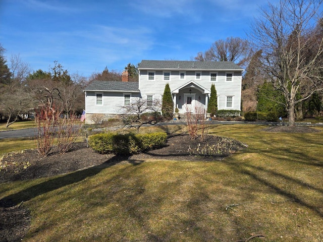 view of front facade with a chimney and a front lawn