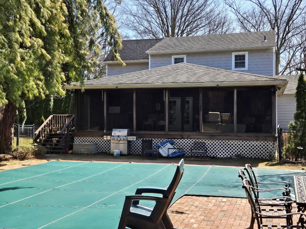 exterior space featuring a fenced in pool, roof with shingles, and a sunroom