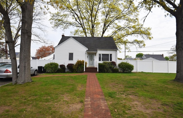 view of front of home featuring fence, a chimney, a shingled roof, and a front yard