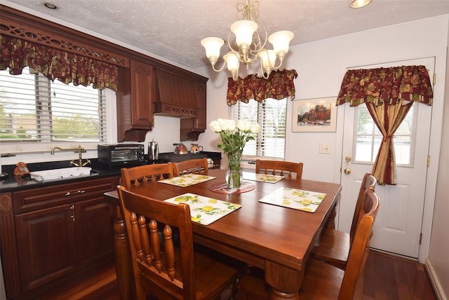 dining space featuring a toaster, dark wood finished floors, a textured ceiling, and a notable chandelier