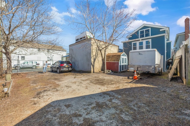 exterior space featuring a storage shed, fence, and an outbuilding