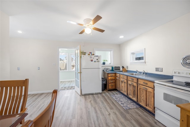 kitchen featuring brown cabinets, light wood-style floors, white appliances, a ceiling fan, and a sink