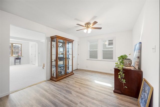 empty room featuring wood finished floors, baseboards, and ceiling fan