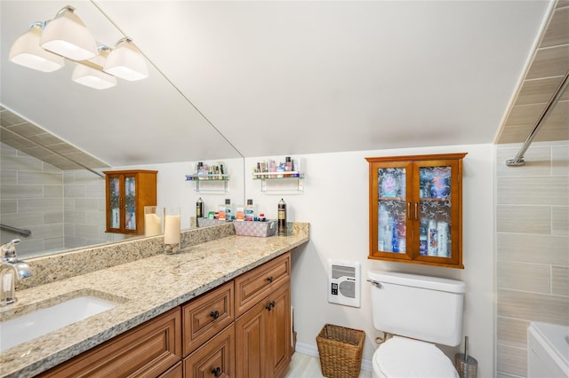 bathroom featuring heating unit, toilet, vanity, and vaulted ceiling