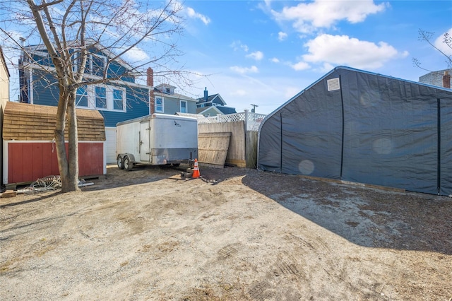 view of yard with a storage shed, an outdoor structure, and fence