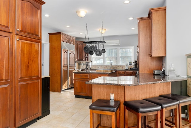 kitchen featuring paneled built in fridge, a peninsula, a breakfast bar area, and dark stone counters