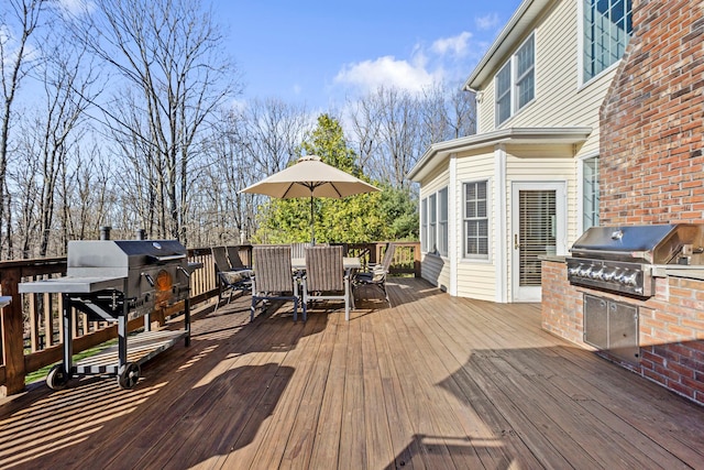 wooden terrace with exterior kitchen, outdoor dining area, and grilling area