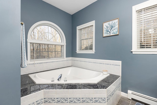 full bathroom featuring a bath, tile patterned flooring, baseboards, and a baseboard radiator