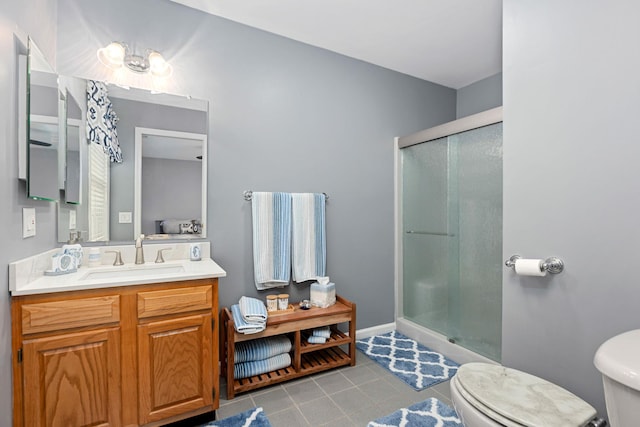 full bathroom featuring tile patterned flooring, baseboards, toilet, a stall shower, and vanity