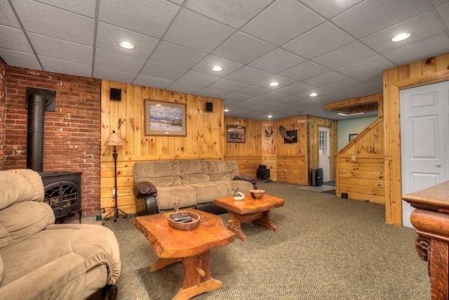 living room with wooden walls, stairs, carpet floors, recessed lighting, and a wood stove