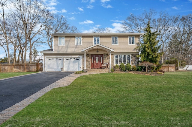 colonial home featuring aphalt driveway, an attached garage, a front lawn, and fence