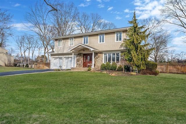 view of front facade with a front yard, an attached garage, fence, and driveway