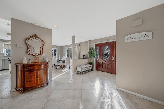 foyer entrance with a wealth of natural light, visible vents, baseboards, and light tile patterned floors