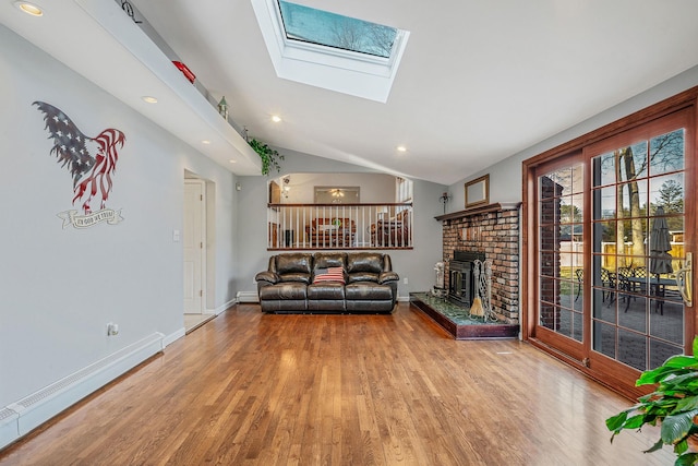 unfurnished living room with lofted ceiling with skylight, a baseboard heating unit, wood finished floors, baseboards, and a brick fireplace