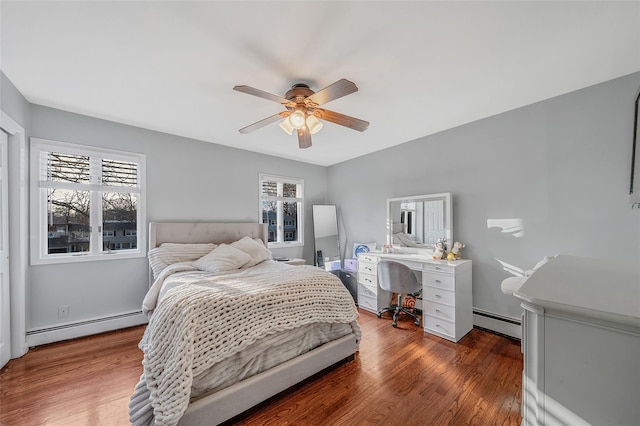 bedroom with a baseboard heating unit, ceiling fan, and wood finished floors