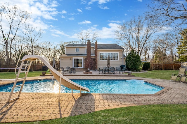 view of pool with a trampoline, a lawn, a fenced in pool, and a water slide