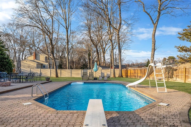 view of pool featuring a patio, a fenced backyard, a water slide, a diving board, and a fenced in pool