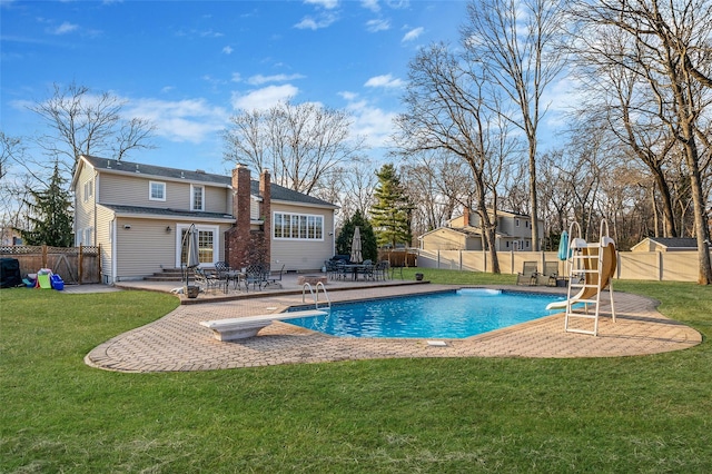 view of pool featuring a yard, a fenced backyard, a diving board, and a water slide