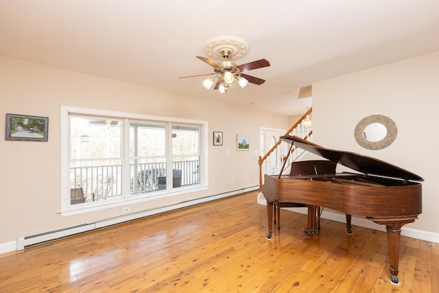 sitting room featuring a baseboard heating unit, baseboards, ceiling fan, stairs, and light wood-style floors